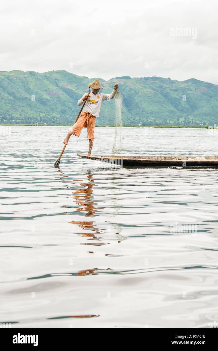 Reisen: Lokale junge Burmesische fischer Tragen von Manchester United Shirt, Lastausgleich und Lenkung Boot mit seinem Fuß in Inle See, Burma, Myanmar, Asien Stockfoto
