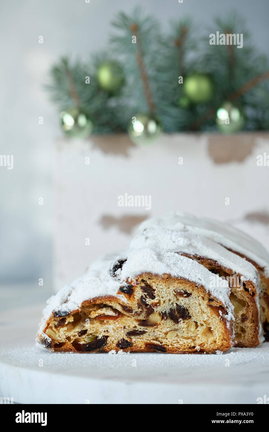 Christstollen auf Weiß festliche Hintergrund mit Tannen Zweigen und Nippes. Traditionelle deutsche Dessert für Weihnachten feiern. Stockfoto