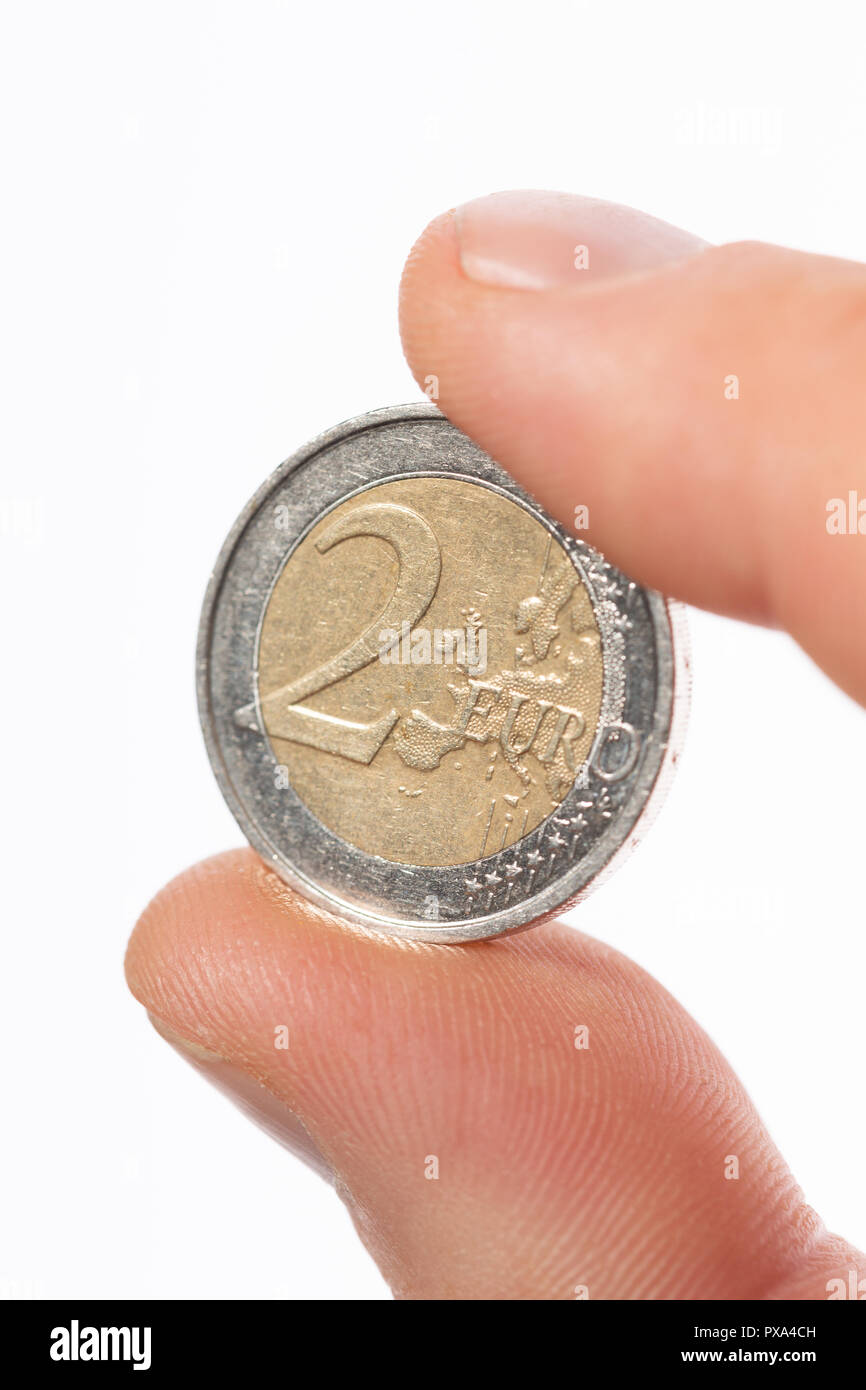 Nahaufnahme der kaukasischen männlichen Finger, der zwei Euro Münze 2 € auf einem weißen Hintergrund. Stockfoto