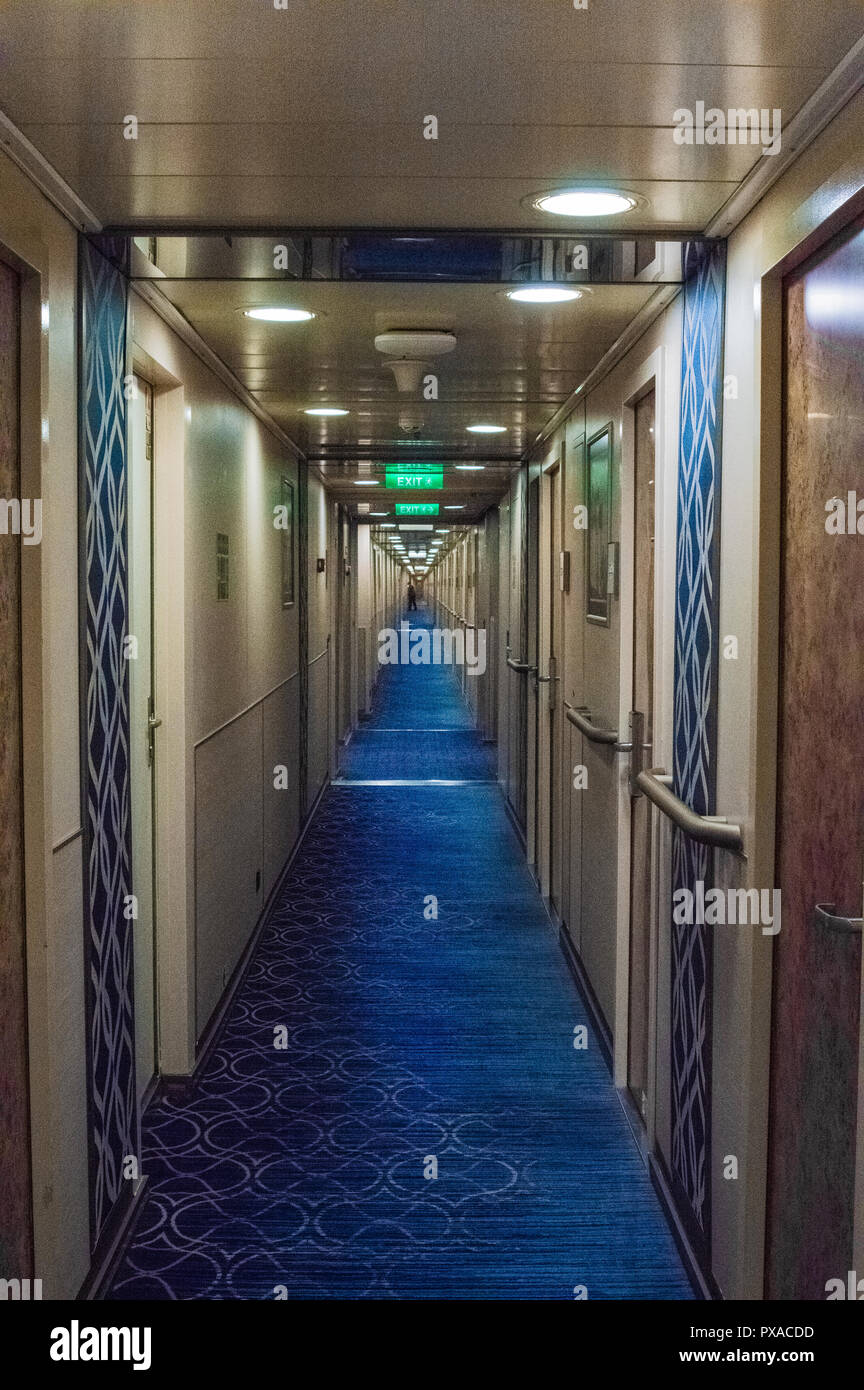 Lange, schmale inneren Durchgang in die Kabinen an Bord Kreuzfahrtschiff, die Grünen den Schildern und Innenbeleuchtung leuchtet wieder zurueck in den Hintergrund. Stockfoto