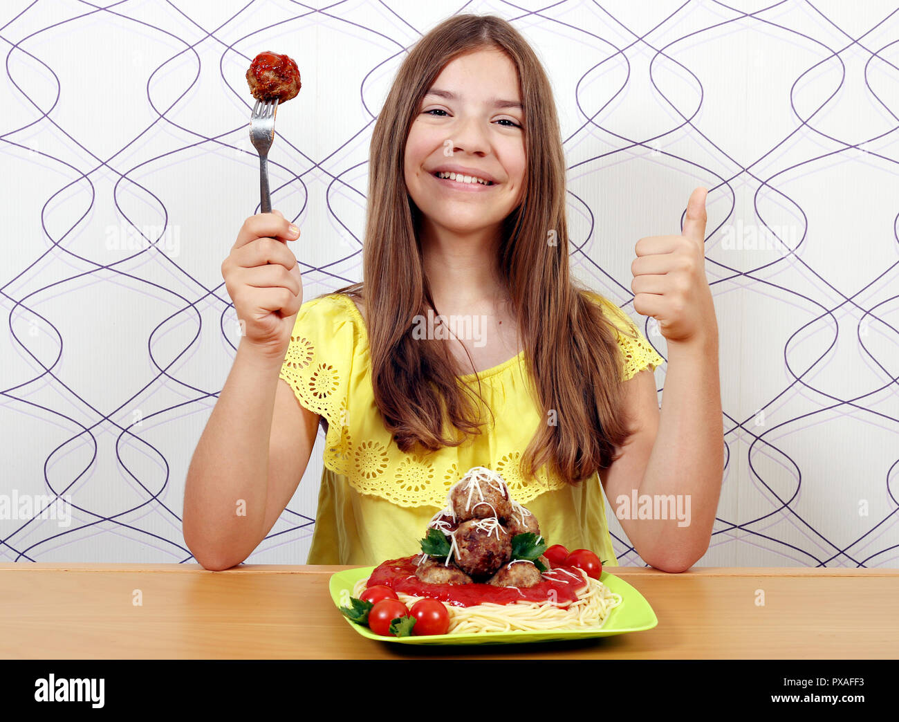 Schöne glückliche Mädchen mit Spaghetti und Frikadellen und Daumen hoch Stockfoto