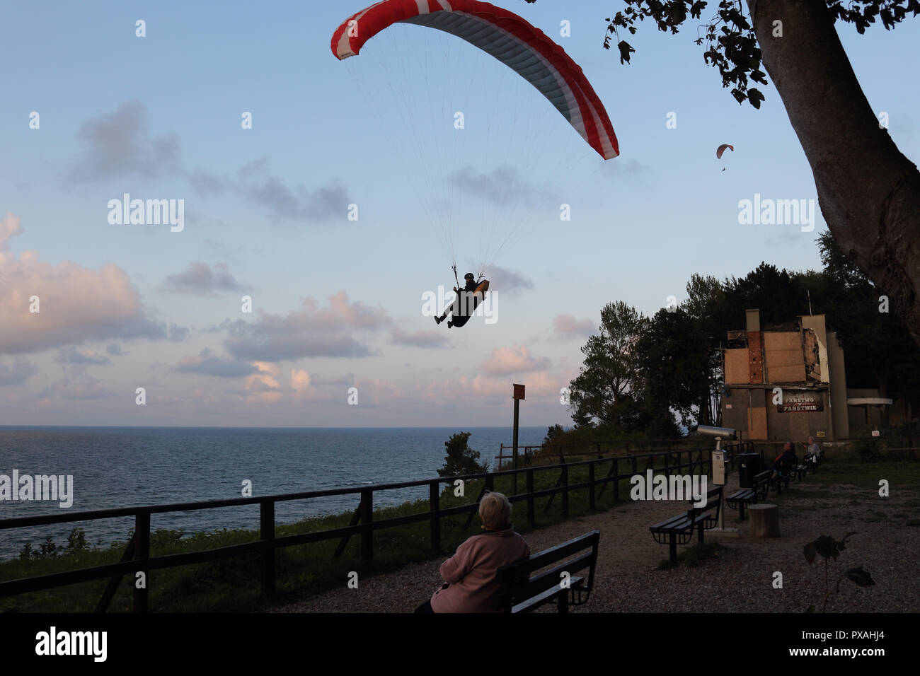 Die Leute sitzen auf Bänken und zwei para Segelflugzeuge über die Ostsee fliegen sehen. Stockfoto