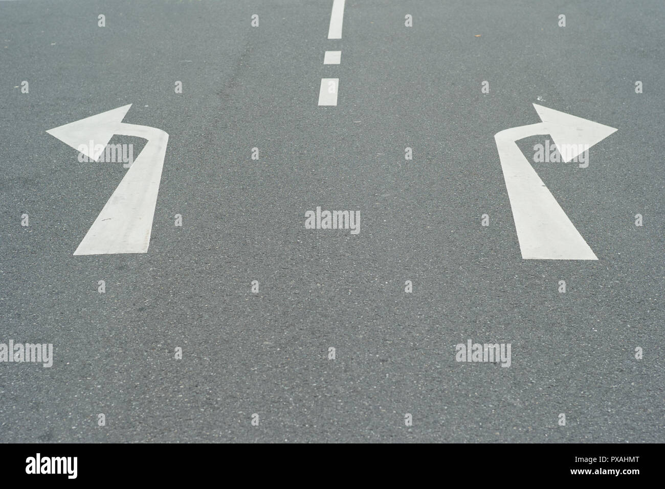 Pfeile nach rechts und nach links auf eine asphaltierte Straße - ein Konzept für Entscheidungen - Durch Drehen nach Links oder Rechts Stockfoto