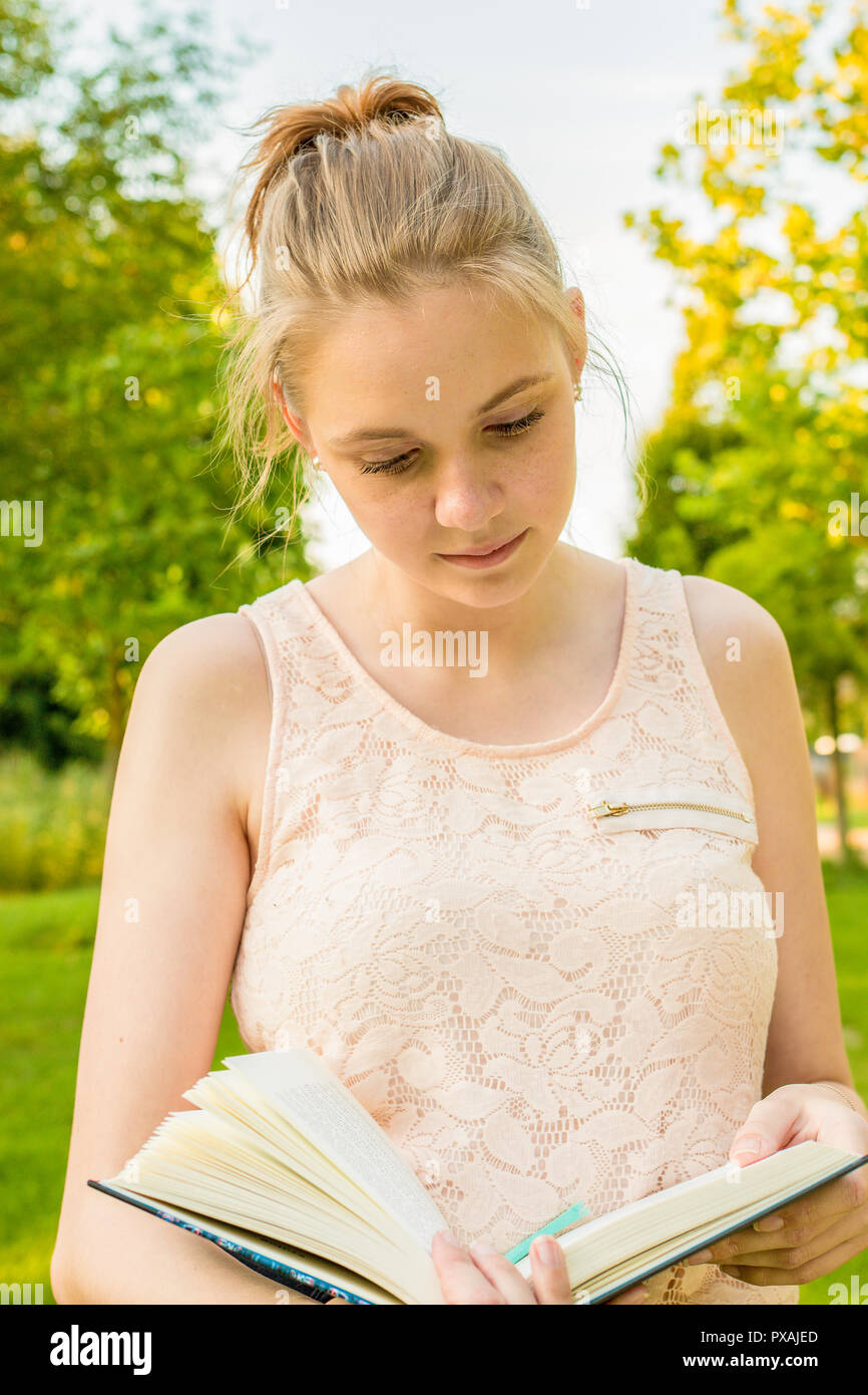 Eine junge Frau, die ein Buch in der Hand in einem Park und einem konzentrierten Art und Weise lesen Stockfoto