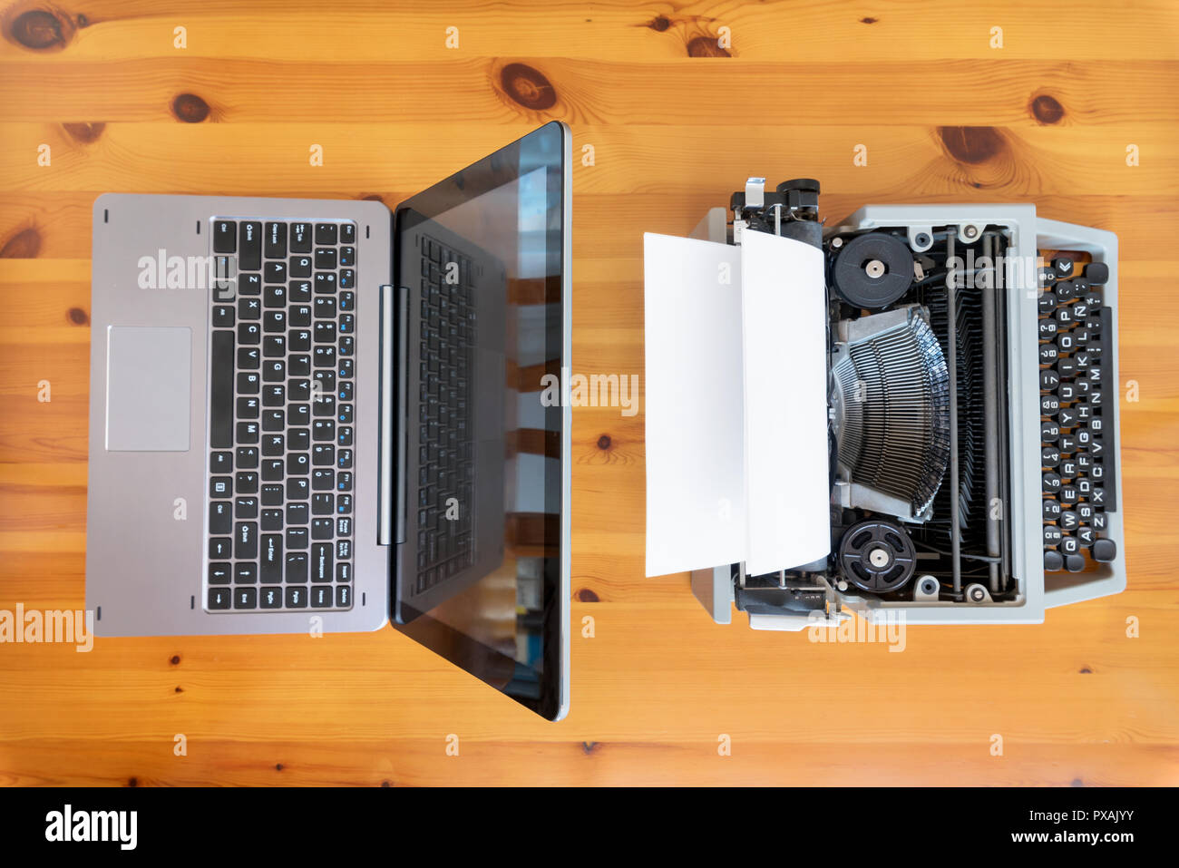 Alte Schreibmaschine vs neue Laptop auf dem Tisch. Konzept der Technologie Fortschritt. Stockfoto