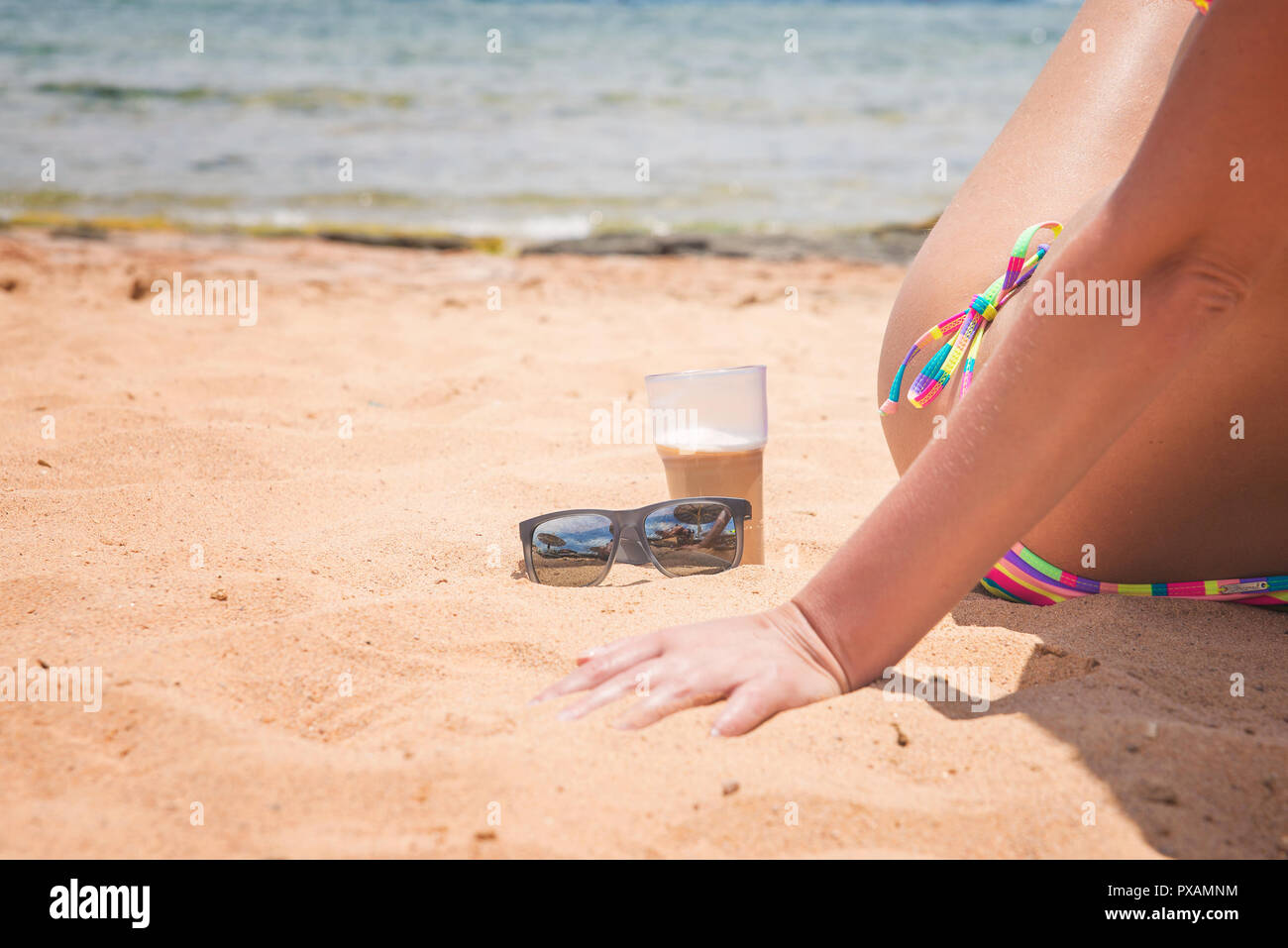 Kaffee und Sonnenbrille auf dem Sand Stockfoto