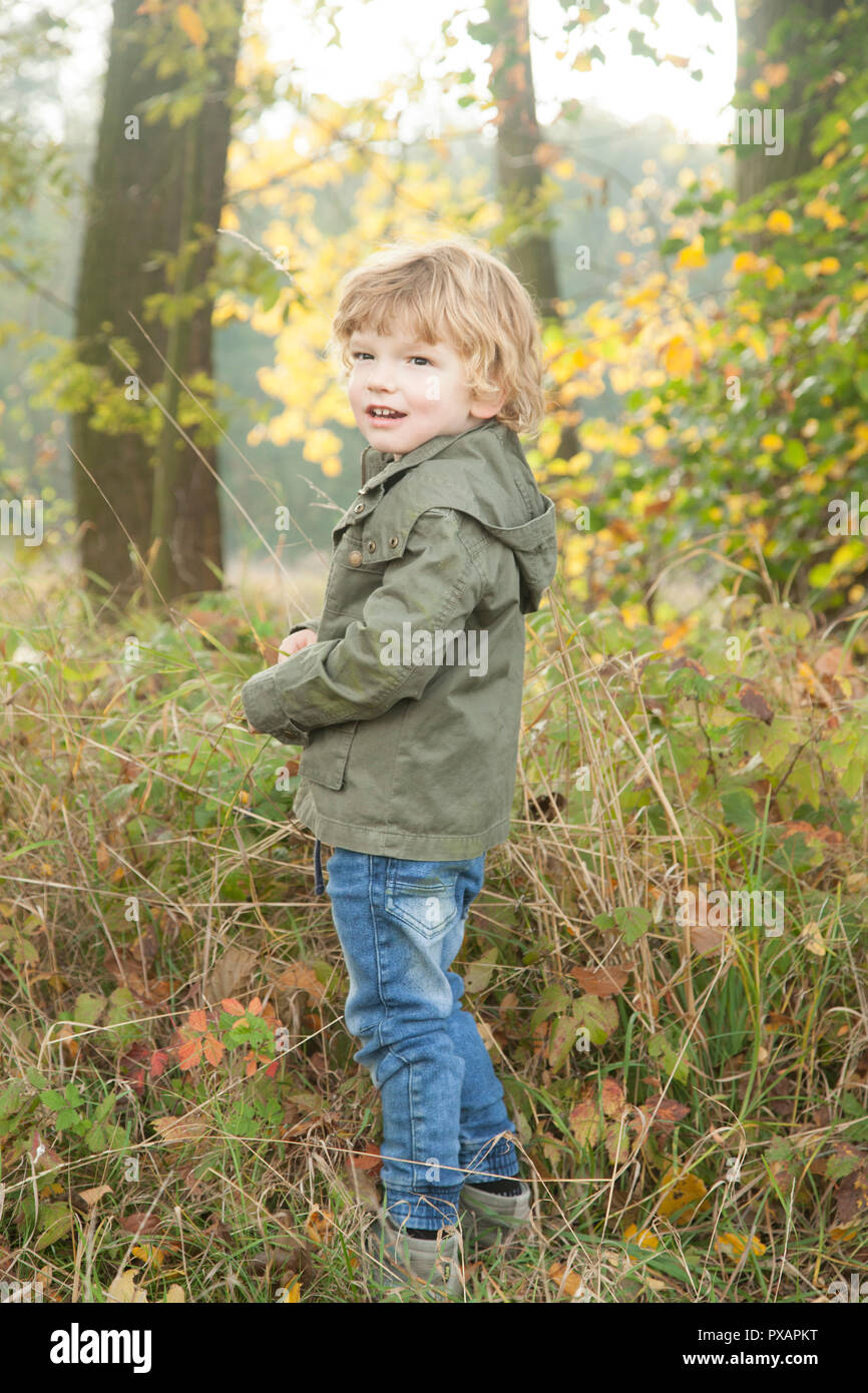 Porträt eines Jungen posiert, und wenn man die Kamera in eine bunte Blätter des Herbstes Wetter in den Wald. Stockfoto