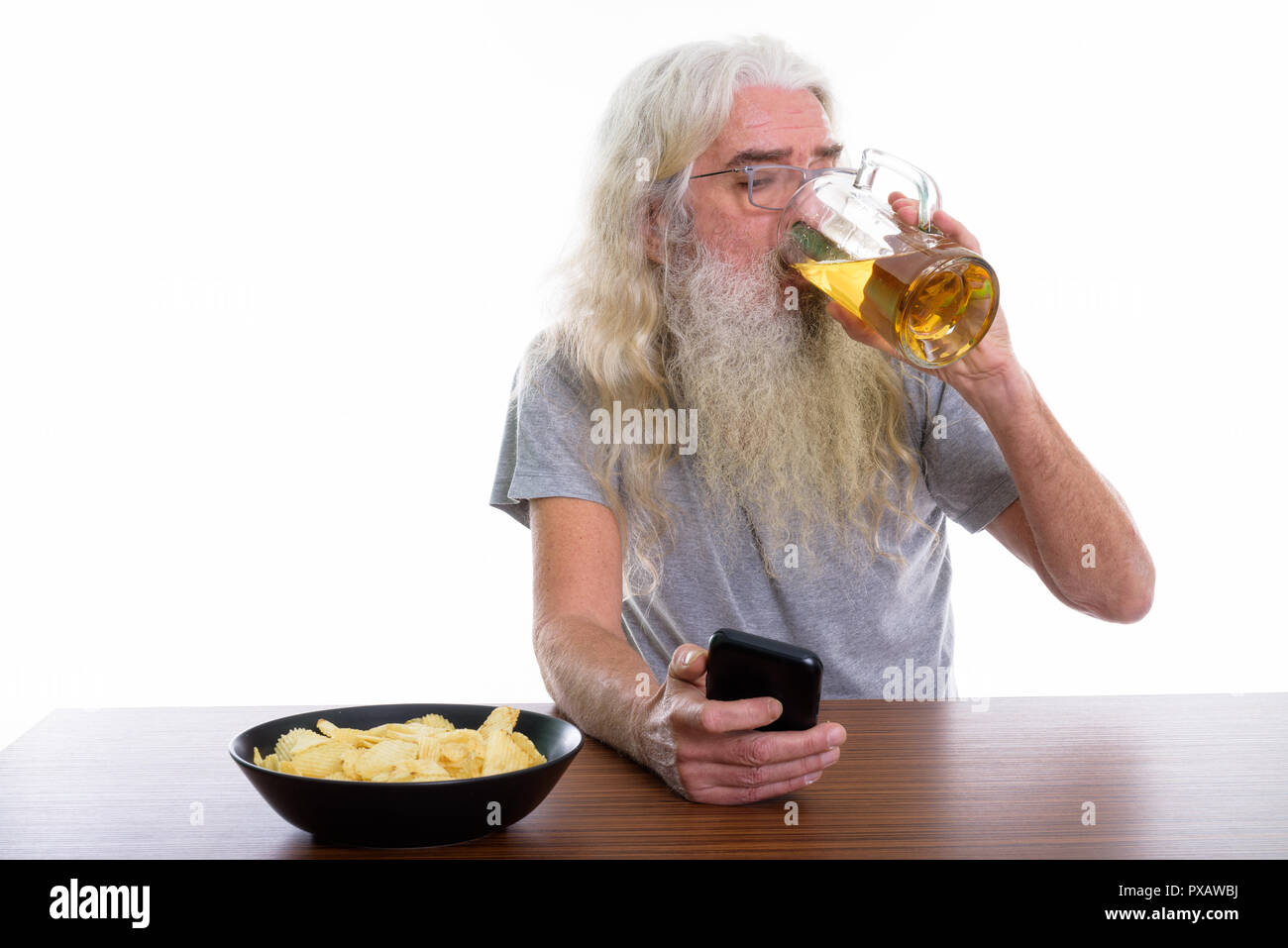 Studio shot der älteren bärtigen Mann mit Handy während trinken Stockfoto
