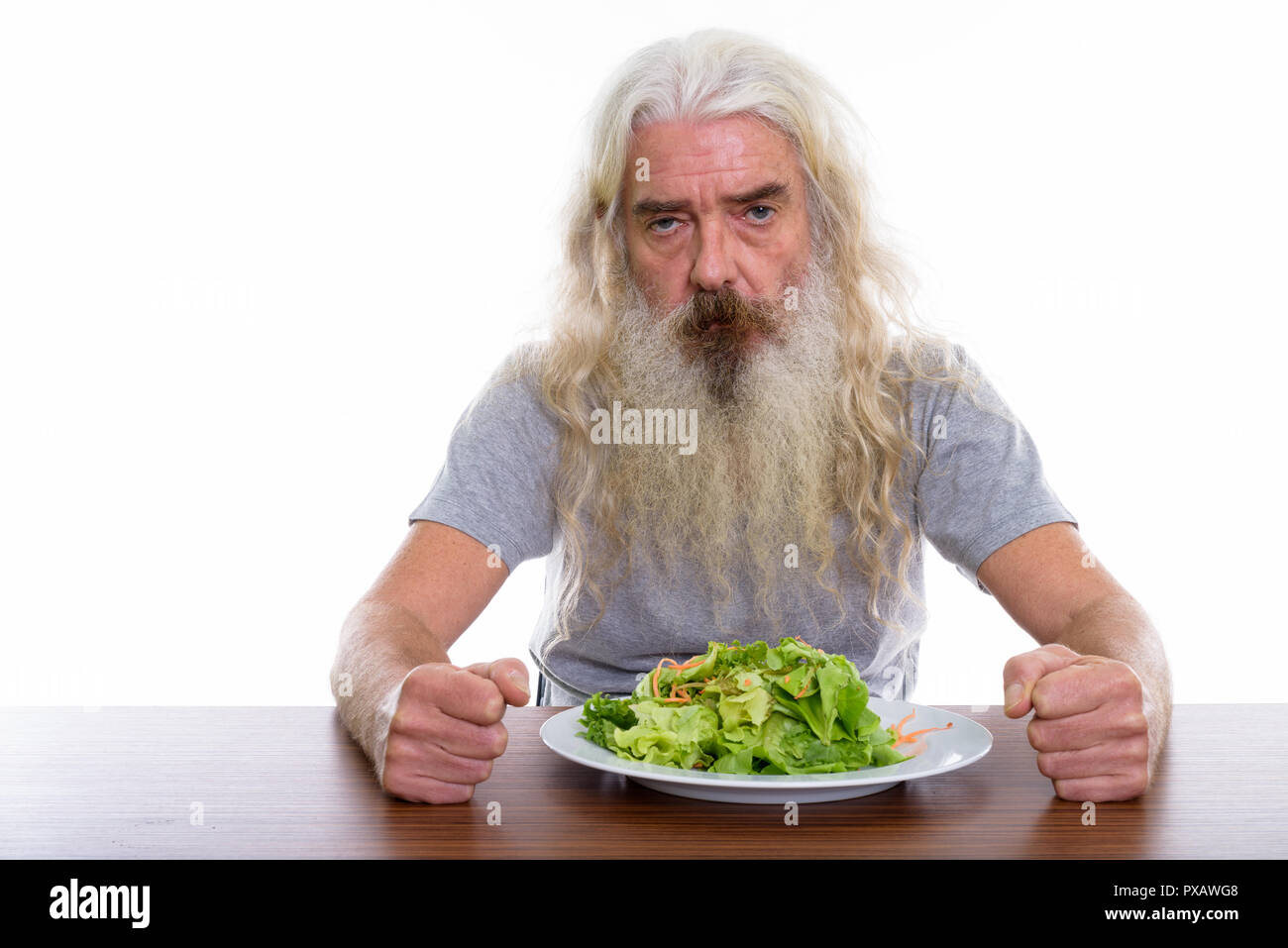 Studio shot der verärgerten älterer bärtiger Mann mit Teller Salat auf w Stockfoto