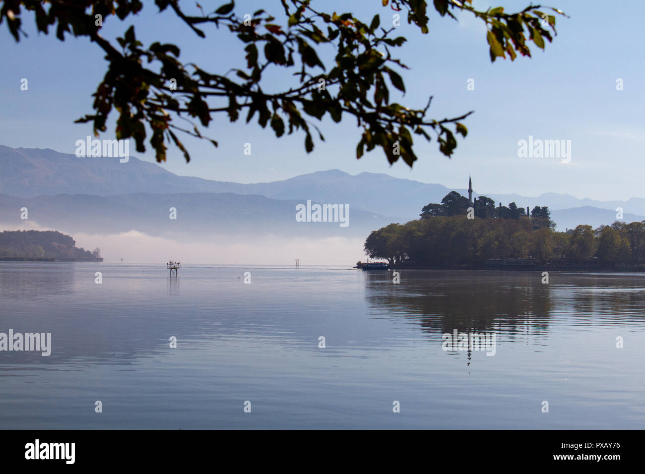Atmosphärische Szene von See Pamvotis an einem nebligen Morgen in Ioannina, Griechenland, mit Aslan Pasha Moschee im Hintergrund Stockfoto