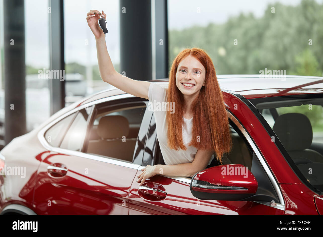 Junge Frau, die von einem neuen Auto im Autohaus überrascht, ein Geschenk  von ihrem Ehemann Stockfotografie - Alamy