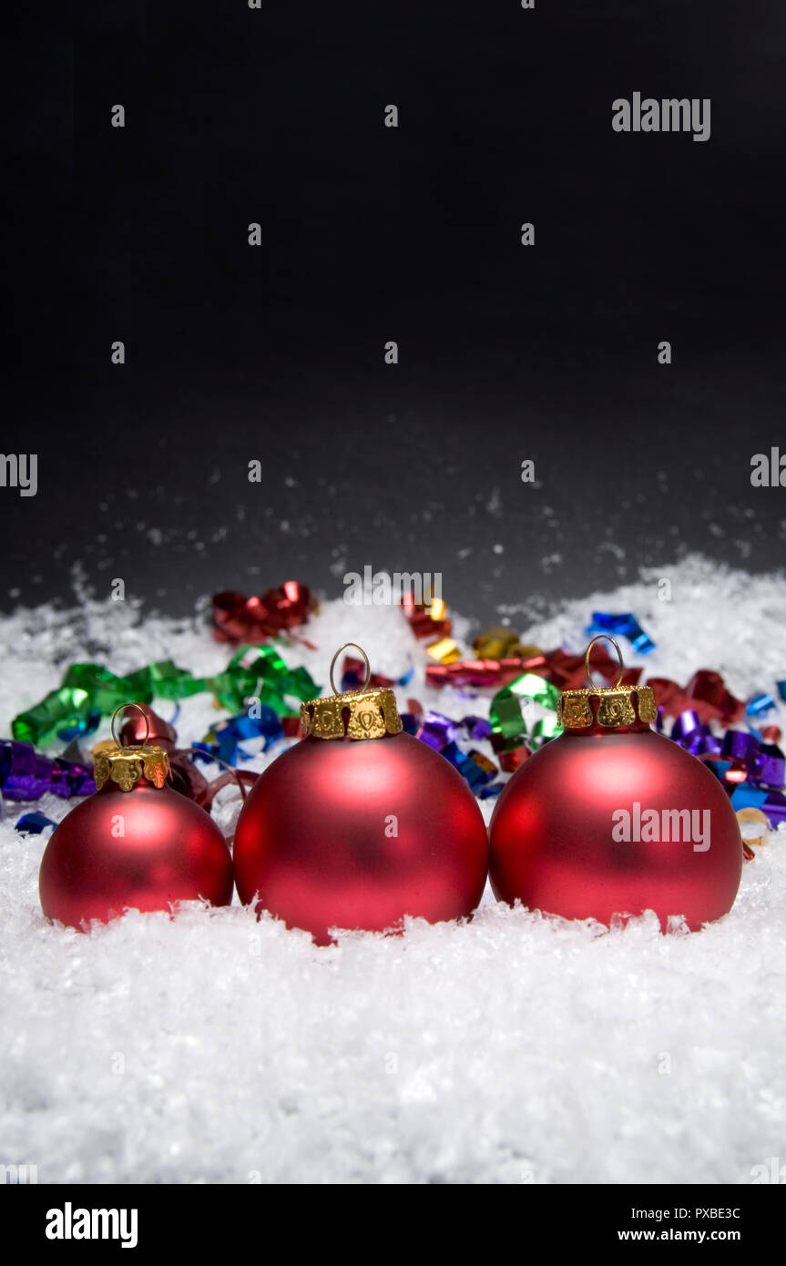 Wunderschöne rote Weihnachtskugeln mit Schnee auf einem dunklen Hintergrund Stockfoto