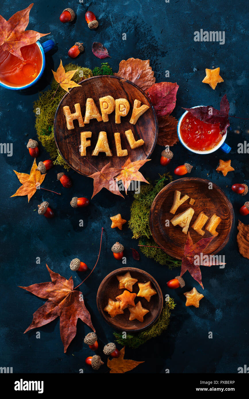 Glücklich fallen Essen Schriftzug mit Cookies. Herbst flach mit Tee, Süßigkeiten und gefallenen Blätter auf einem dunklen Hintergrund mit Kopie Raum Stockfoto
