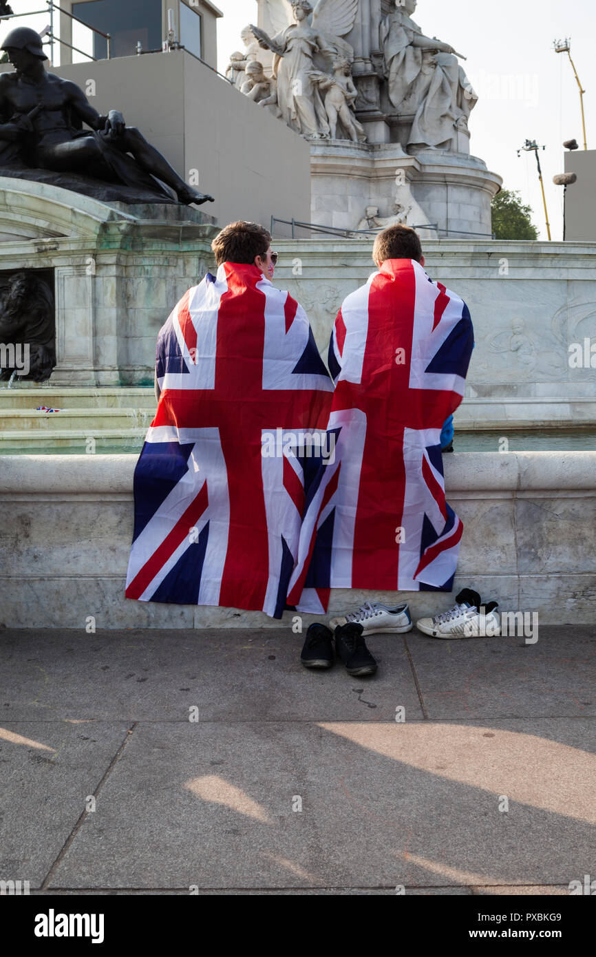 Zwei junge Männer in Union Jack Fahnen eingewickelt und kühlen ihre Füße im Brunnen vor dem Buckingham Palace. Stockfoto