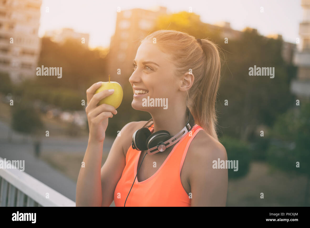 Schöne sportliche Frau essen Apple beim Stillstehen aus Übung Stockfoto