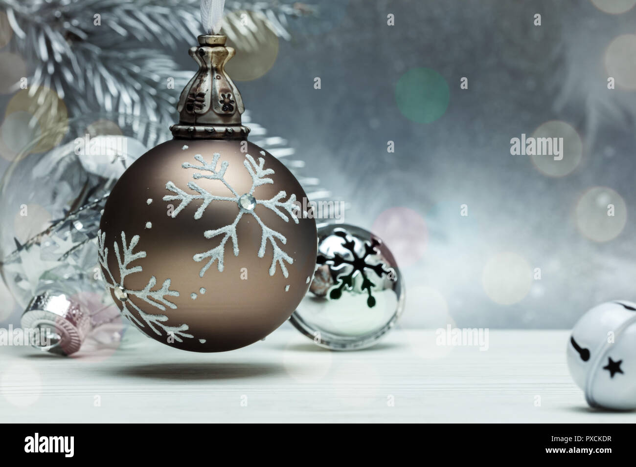 Dekorativen Kugeln aus Glas und Jingle bells für Weihnachtsbaum auf grauem Hintergrund mit unscharfen Fir Tree Branch Stockfoto