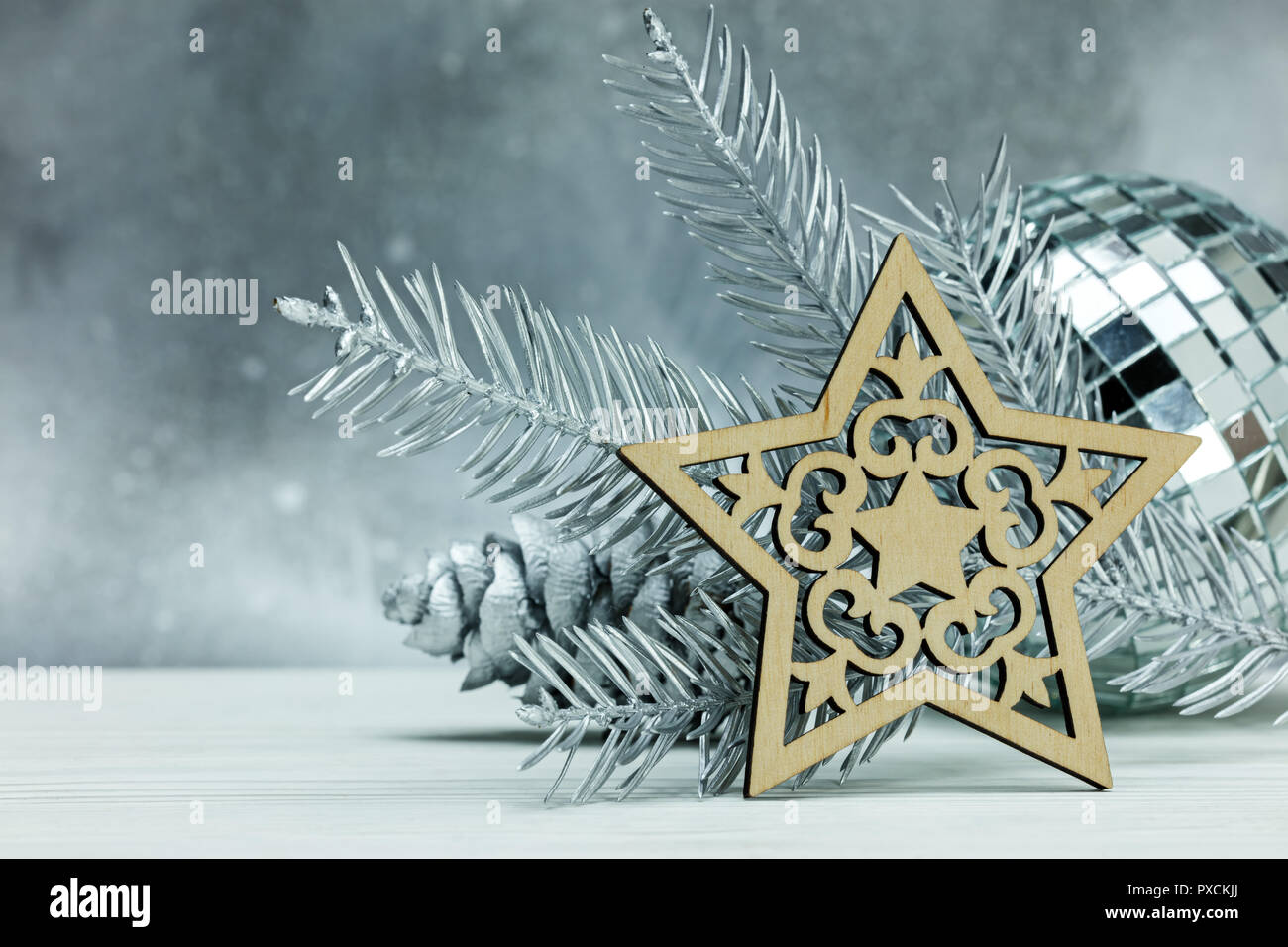 Dekoratives aus Holz geschnitzte Sterne silber christmas ball und Fir Tree Branch gegen Grau verschwommenen Hintergrund Stockfoto