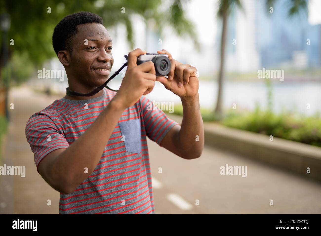Junge schöne afrikanischer Mann Aufnehmen von Bildern mit der Kamera im Park Stockfoto