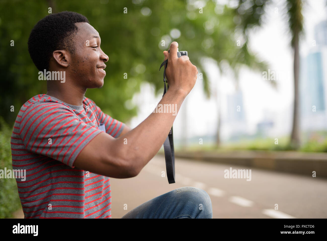 Junge schöne afrikanischer Mann Aufnehmen von Bildern mit der Kamera im Park Stockfoto
