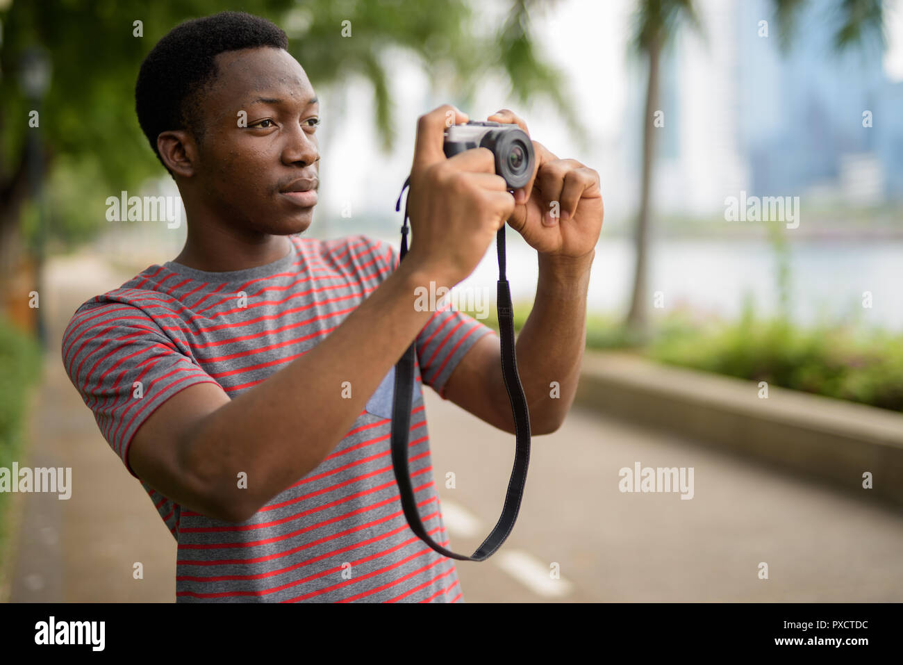 Junge schöne afrikanischer Mann Aufnehmen von Bildern mit der Kamera im Park Stockfoto