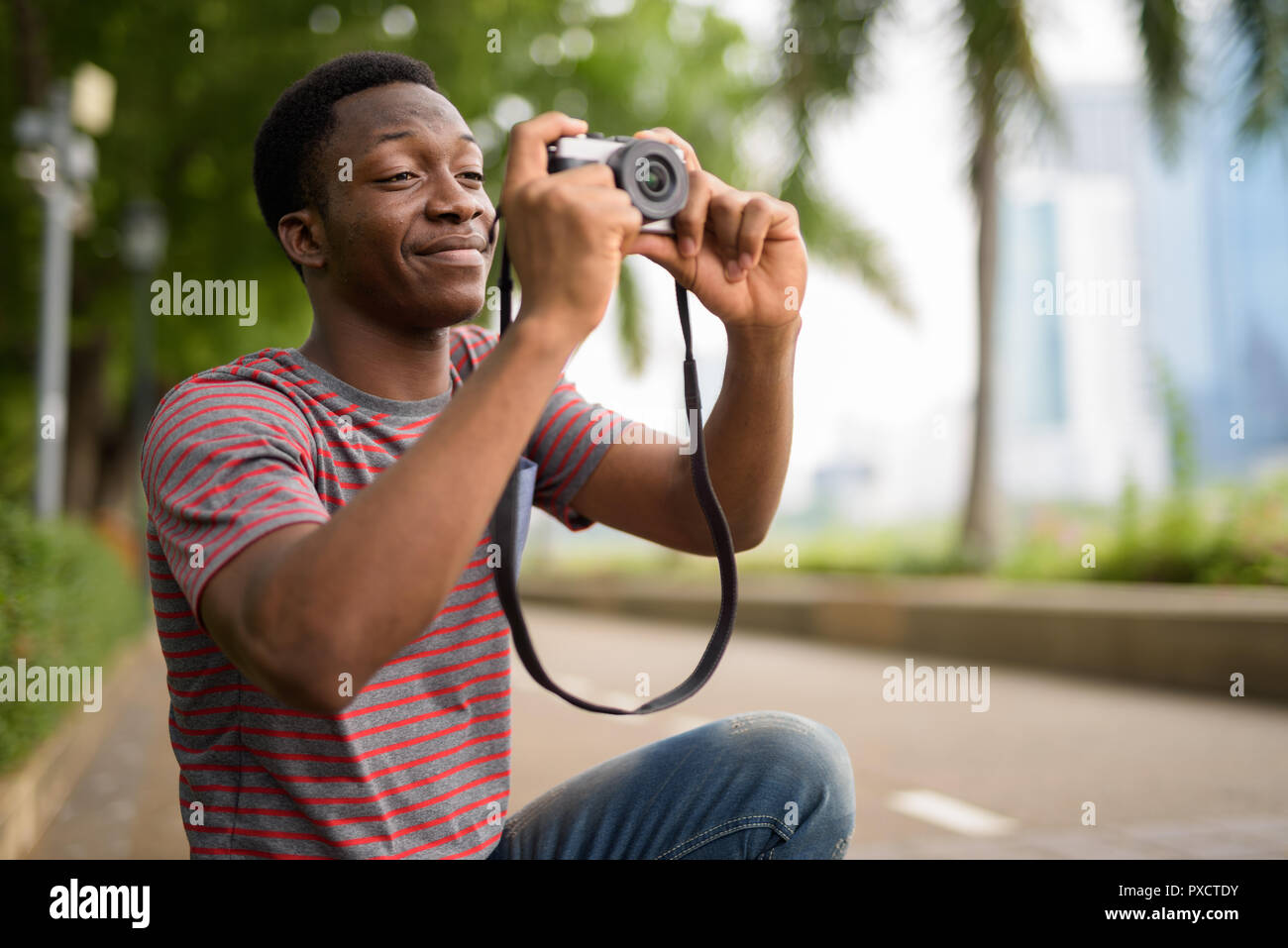 Junge schöne afrikanischer Mann Aufnehmen von Bildern mit der Kamera im Park Stockfoto
