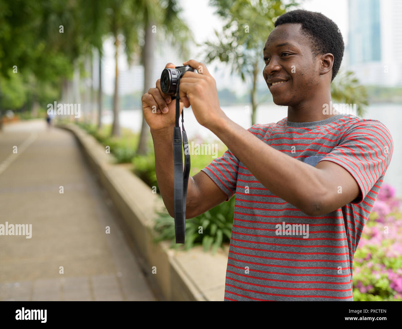 Junge schöne afrikanischer Mann Aufnehmen von Bildern mit der Kamera im Park Stockfoto