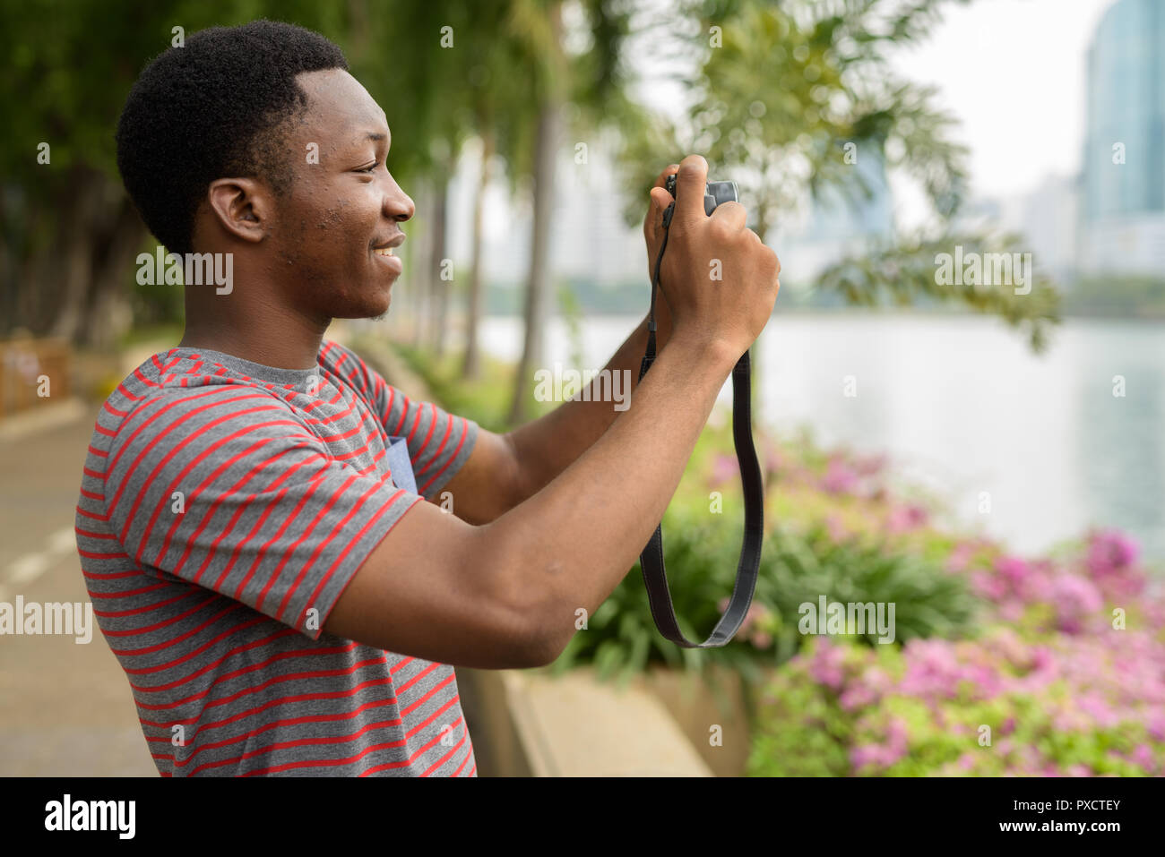 Junge schöne afrikanischer Mann Aufnehmen von Bildern mit der Kamera im Park Stockfoto
