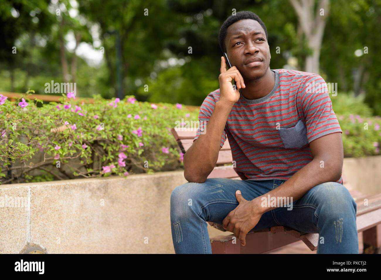 Junge schöne afrikanischer Mann am Telefon sprechen in Park Stockfoto