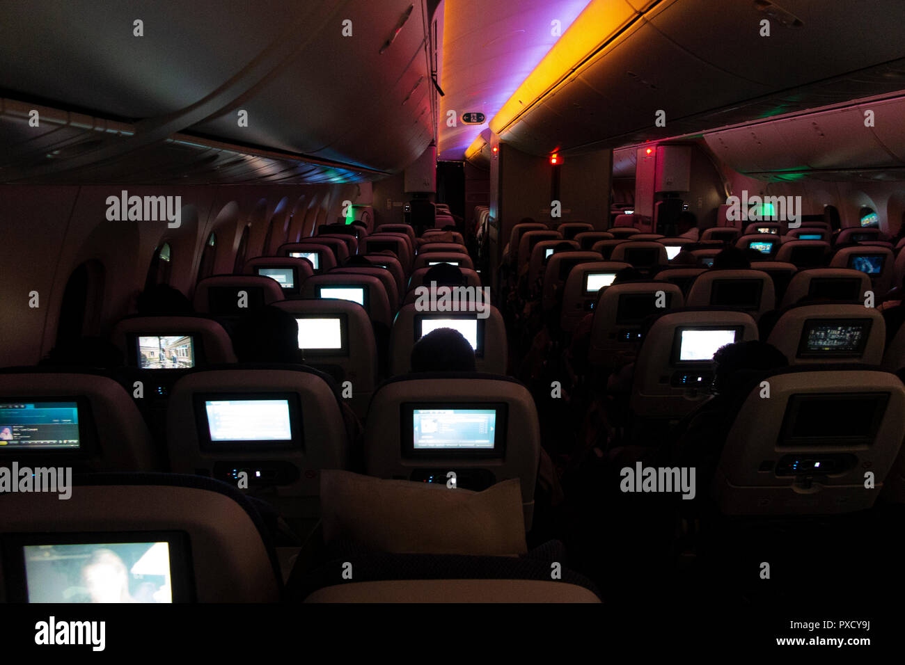 Video Bildschirme leuchten, das Innere von einem Langstreckenflug auf einer BA 777 bei Nacht Stockfoto