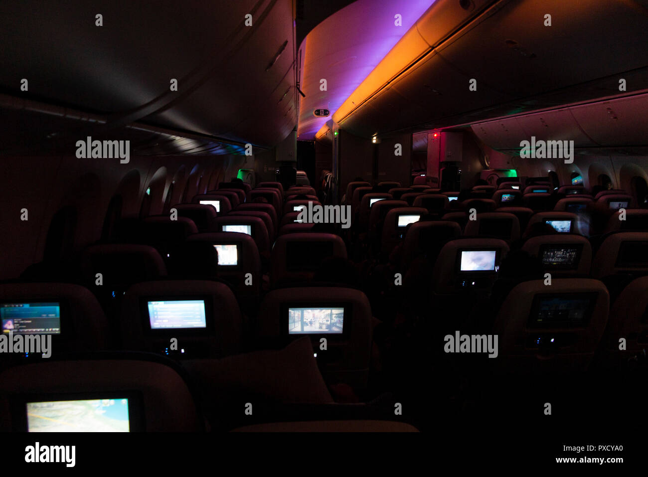 Video Bildschirme leuchten, das Innere von einem Langstreckenflug auf einer BA 777 bei Nacht Stockfoto