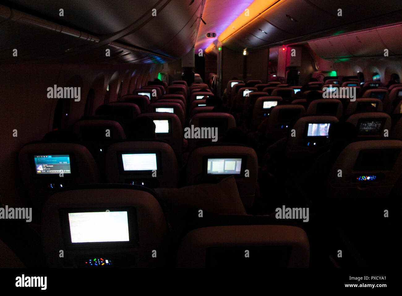 Video Bildschirme leuchten, das Innere von einem Langstreckenflug auf einer BA 777 bei Nacht Stockfoto