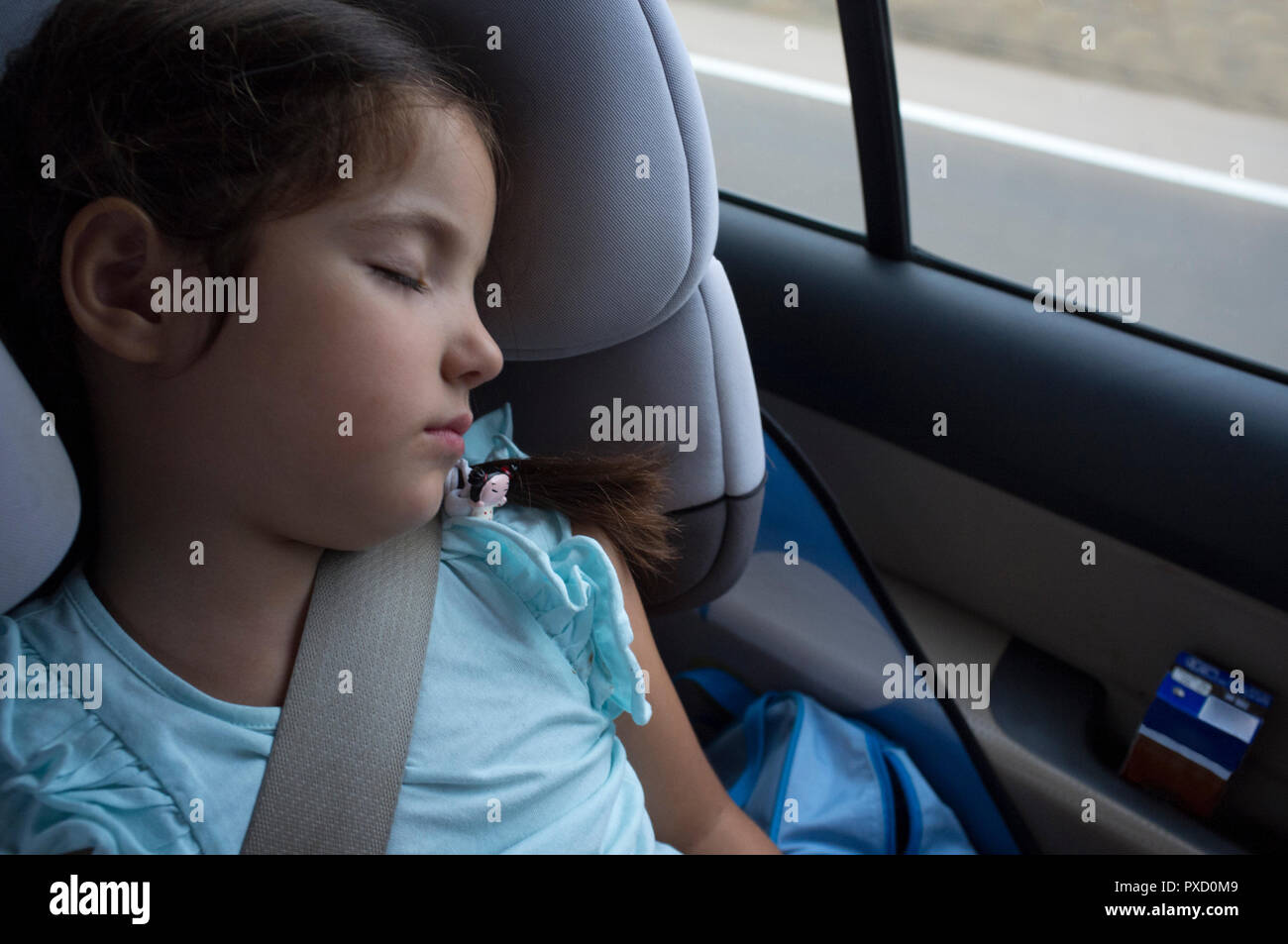 Kind Mädchen schlafen in einem Kindersitz während der Reise. Sie ist eine aus Backstein Milchshake auf Auto Tür Stockfoto
