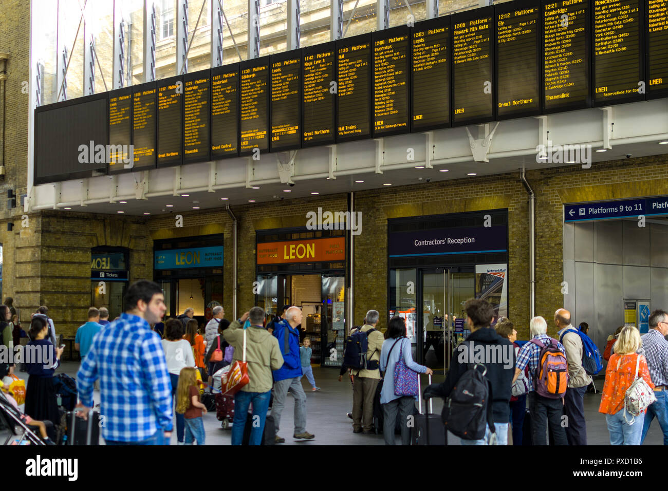 Pendler, der an der Zentrale elektronische Zug Aushänge in der halle des Bahnhof King's Cross, London, UK Stockfoto