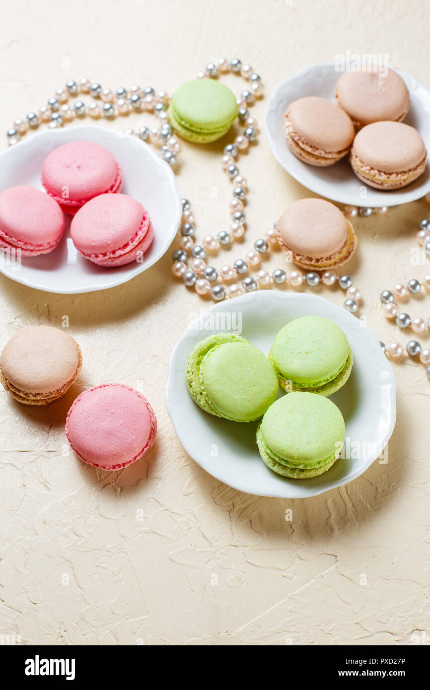 Drei Platten mit Makronen rosa, grün und braun und Perle Perlen auf den Tisch Stockfoto