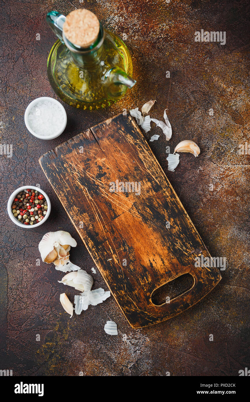 Holz Schneidebrett, Olivenöl, Salz, Pfeffer, Knoblauch und Thymian Zweige auf einem dunklen Hintergrund. Ansicht von oben Kopieren Raum Stockfoto