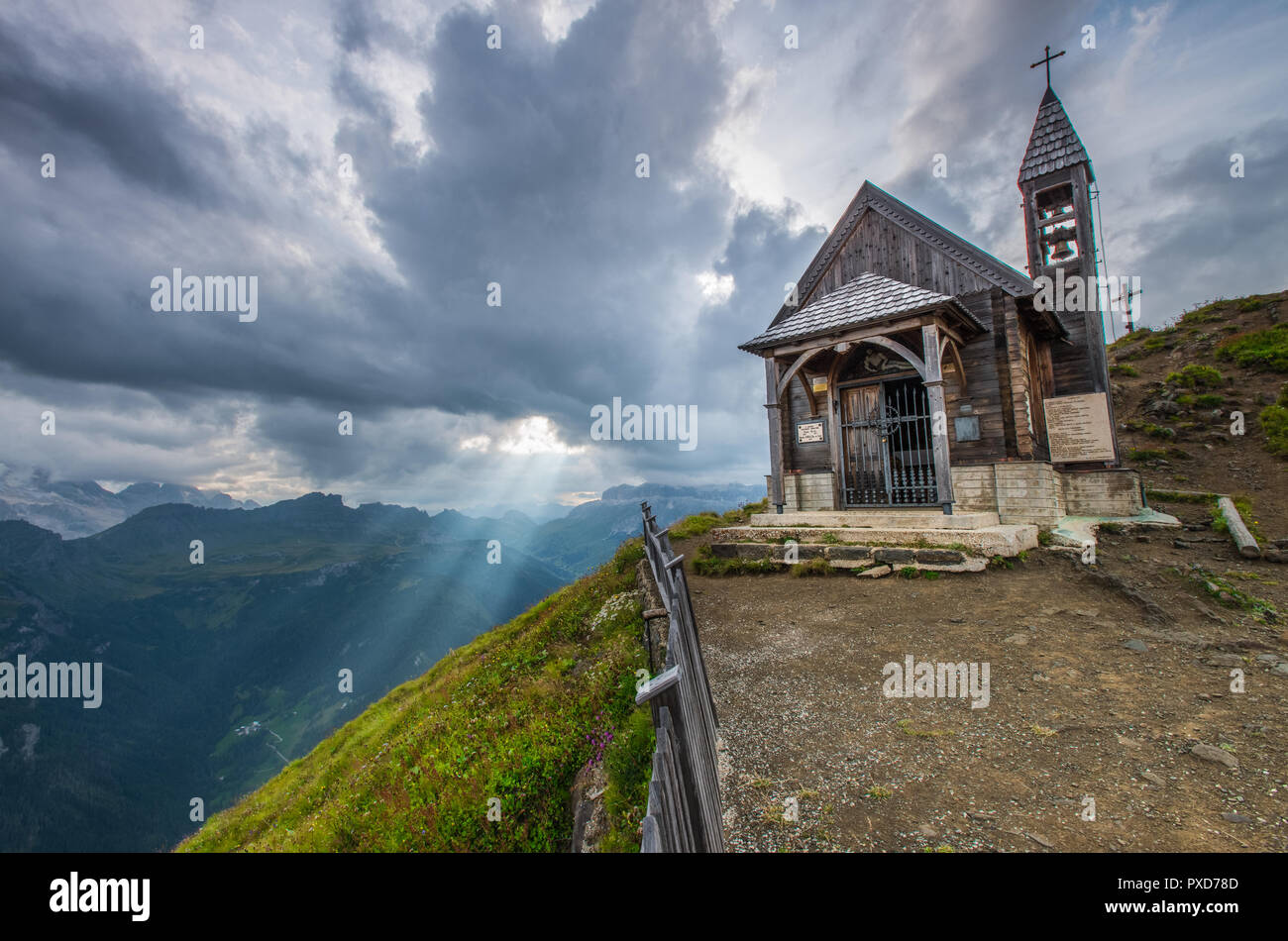 Die hölzerne Kirche, die auf dem Gipfel dieses Berges in den italienischen Alpen. Sunbeam, sunray Filterung durch die Wolken. Heiliges Licht vom Himmel. Glockenturm. Stockfoto
