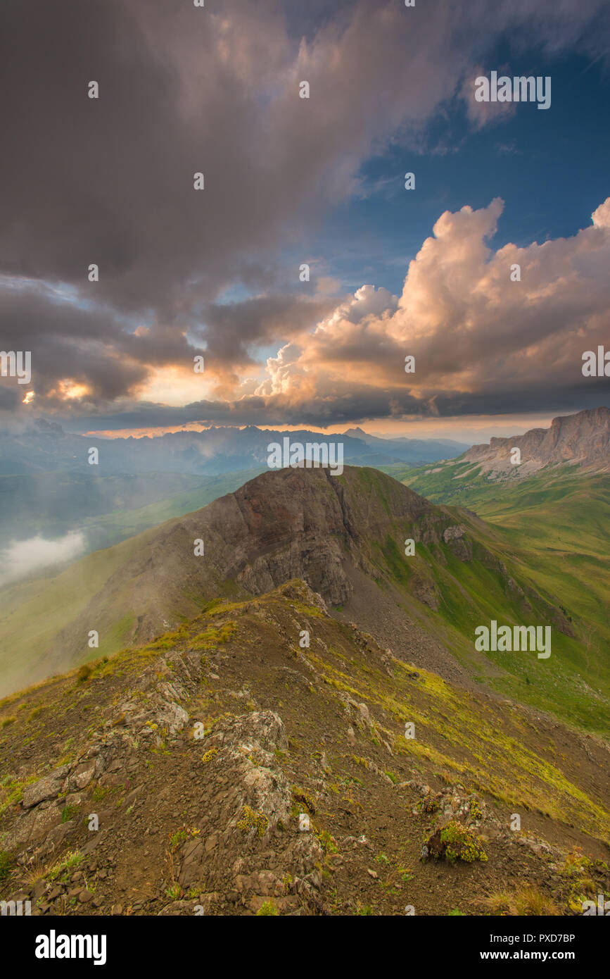 Beeindruckende Gipfel Blick auf eine bunte, lebendige Sonnenuntergang auf einer Bergspitze in Italien der Alpen, Dolomiten. Gemalten Himmel bei Sonnenuntergang, Tal, Gras, niedrige Wolken. Stockfoto