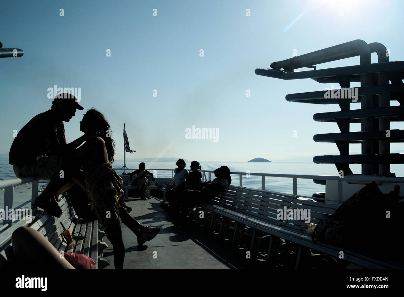 Griechenland, eine kleine Inselfähre, fährt über die Ägäis. Urlauber können die Sommersonne auf der Dachterrasse genießen. Die Menschen beginnen ihren Urlaub. Stockfoto