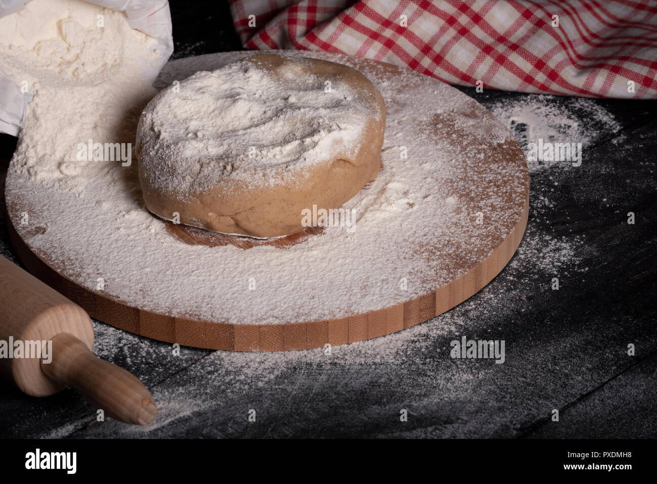 Mehlig Holzplatte auf einer schwarzen Küche Tisch, mit einem Stück Lebkuchen Teig auf es Stockfoto