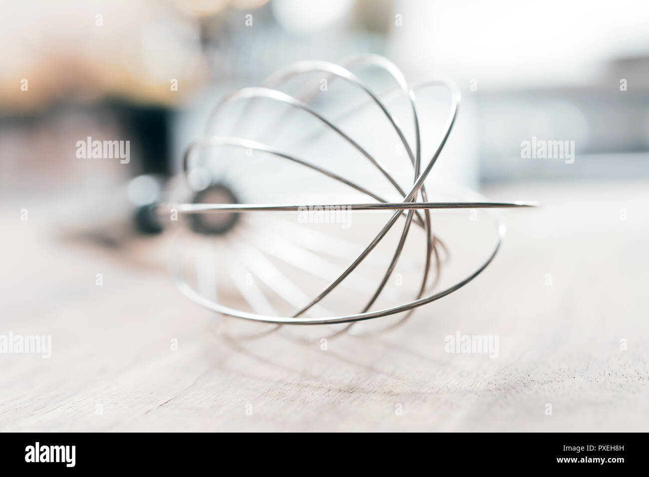 Edelstahl Schneebesen auf einem Holztisch mit unscharfen Hintergrund, Küche Stockfoto