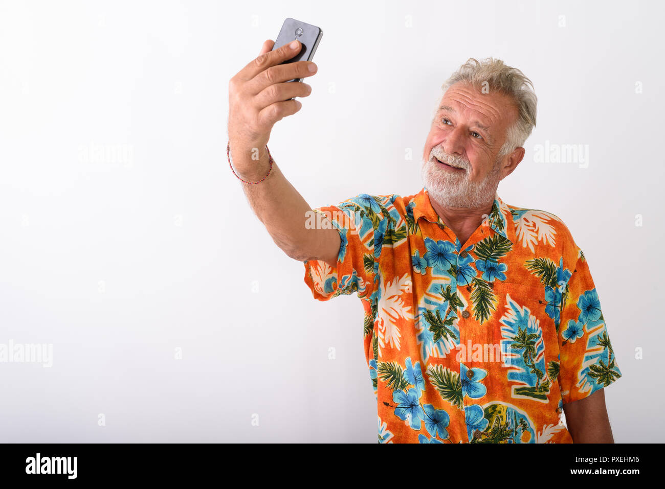 Studio shot von Happy senior Bärtigen touristische Mann lächelnd, während ta Stockfoto