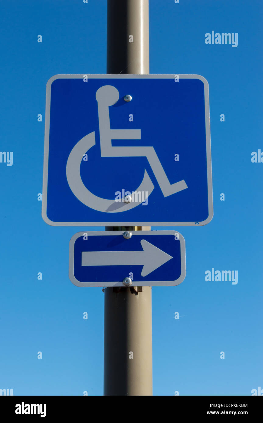 Behindertenparkplätze Zeichen auf Pole in Parkplatz mit nach rechts gerichteter Pfeil Stockfoto
