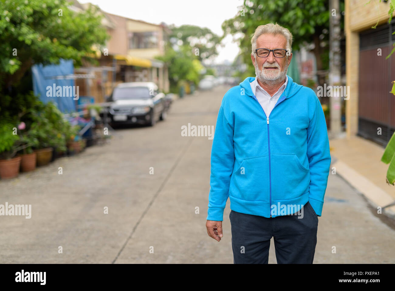 Gut aussehender älterer bärtiger Mann trägt blaue Jacke und Brille o Stockfoto
