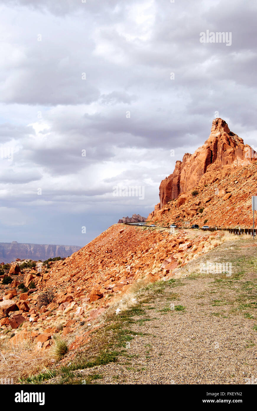 Die Straße mit Autos durch die Wüste, Berge und rotes beeindruckenden Felsen von Arizona, USA, mit einem weißen bewölkter Himmel im Hintergrund Stockfoto