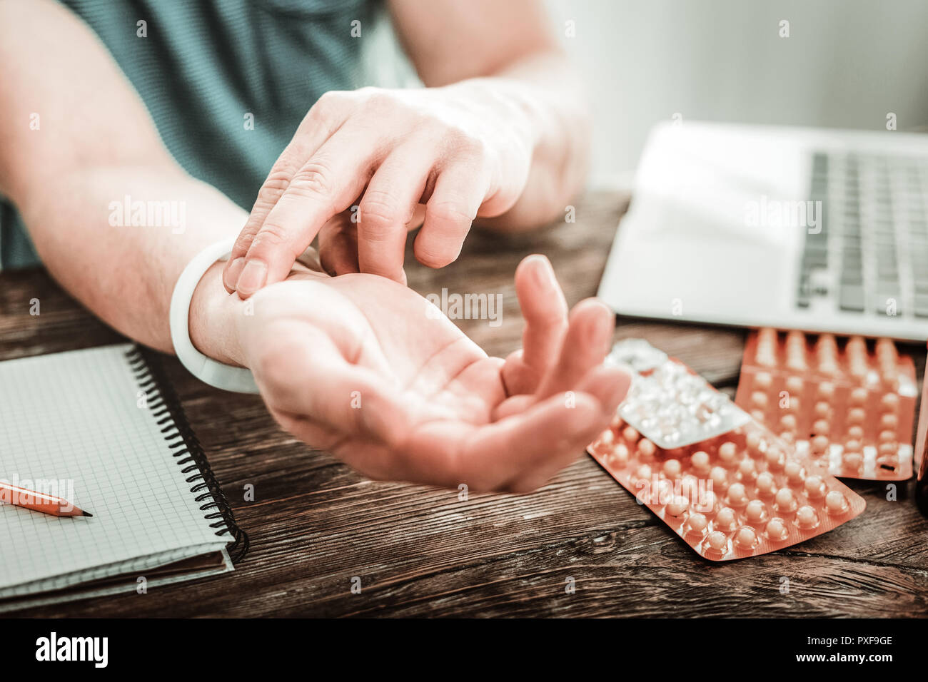Angenehm schöner Mann, der versucht, seinen Puls zu messen. Stockfoto