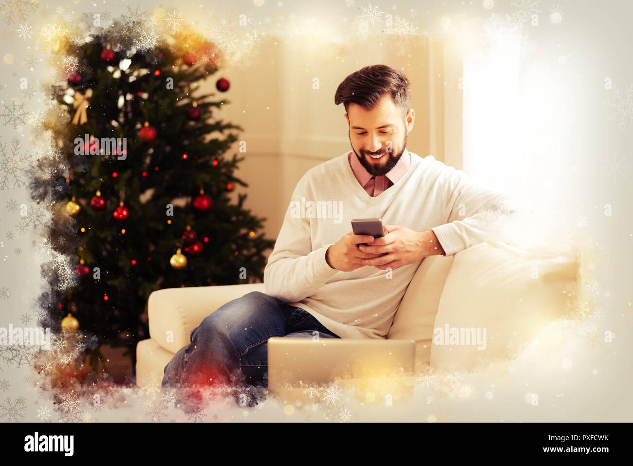 Strahlende dunkelhaarige Mann sitzt auf beige Sofa im Wohnzimmer warten auf Frau Stockfoto