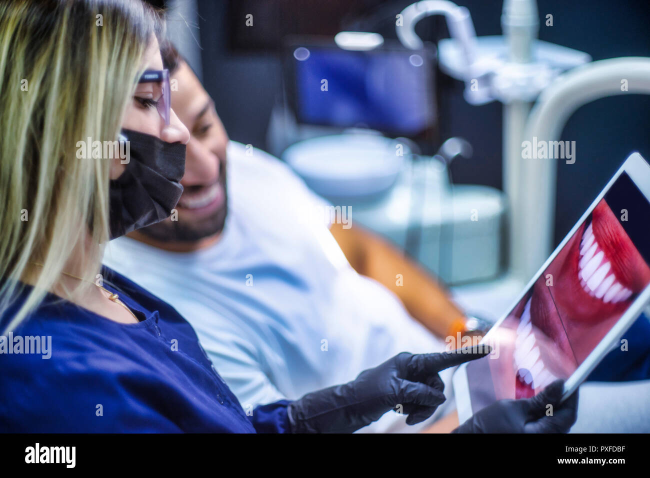 Weiblichen Zahnarzt zeigt elektronisches Gerät für männliche Patienten für Smile design Stockfoto