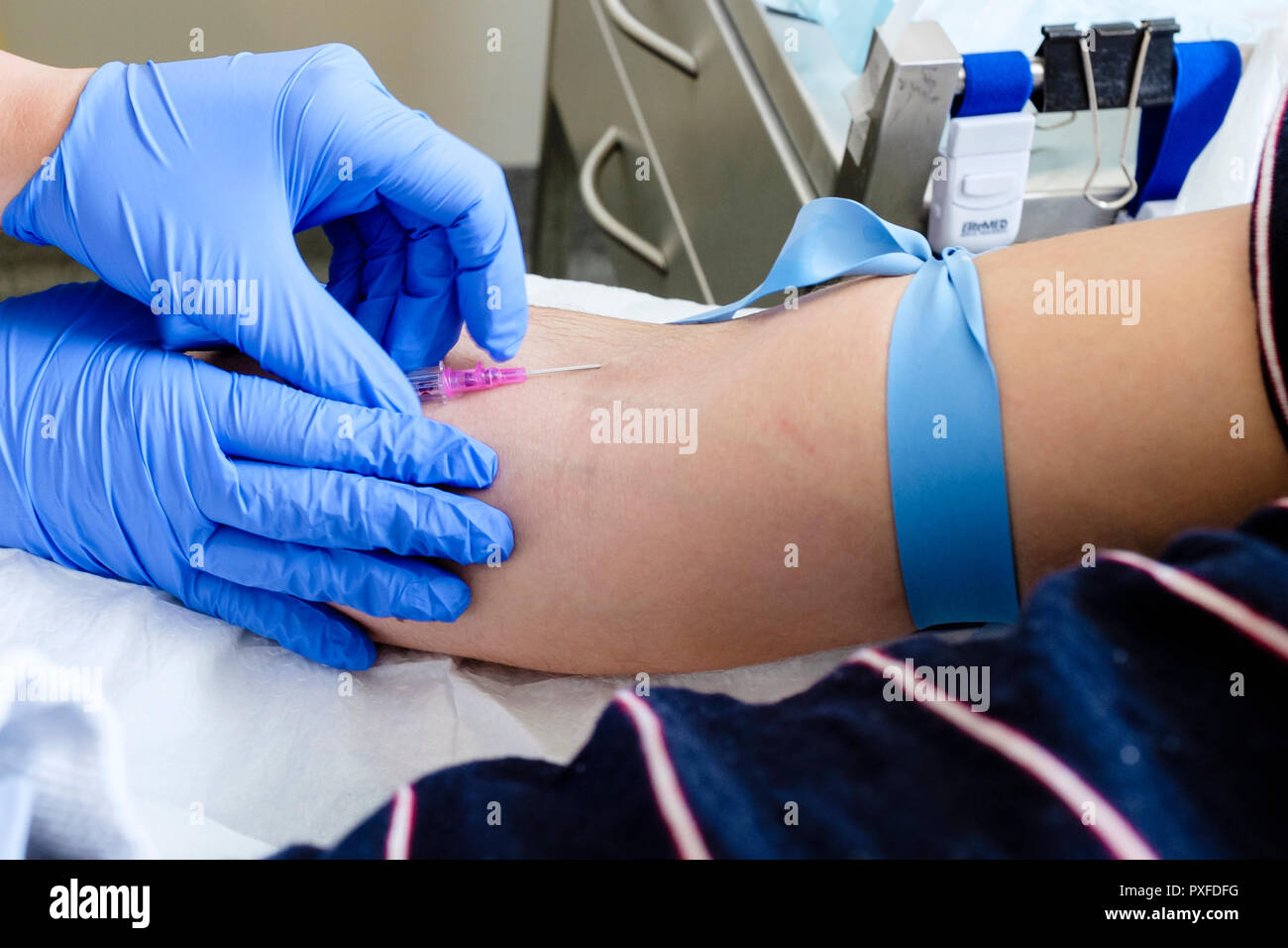 Krankenschwester einfügen Nadel für IV-Kanüle in den Arm des Patienten mit tourniquet in der Notaufnahme im Krankenhaus in Australien, Oktober 2018 Stockfoto