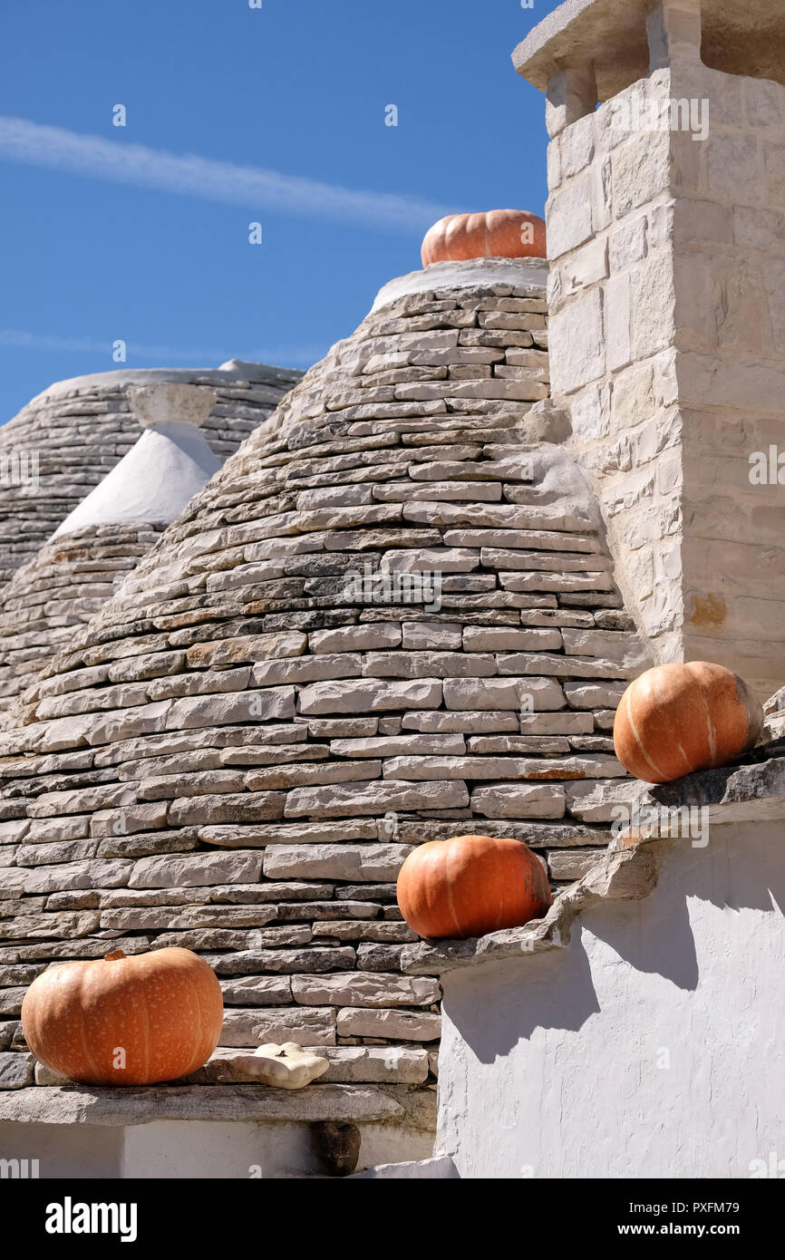 Gruppe von Trockenmauern Trulli auf einer Straße in der Aia Piccola Wohngegend von Alberobello. Kürbisse auf die traufe Halloween zu feiern. Stockfoto