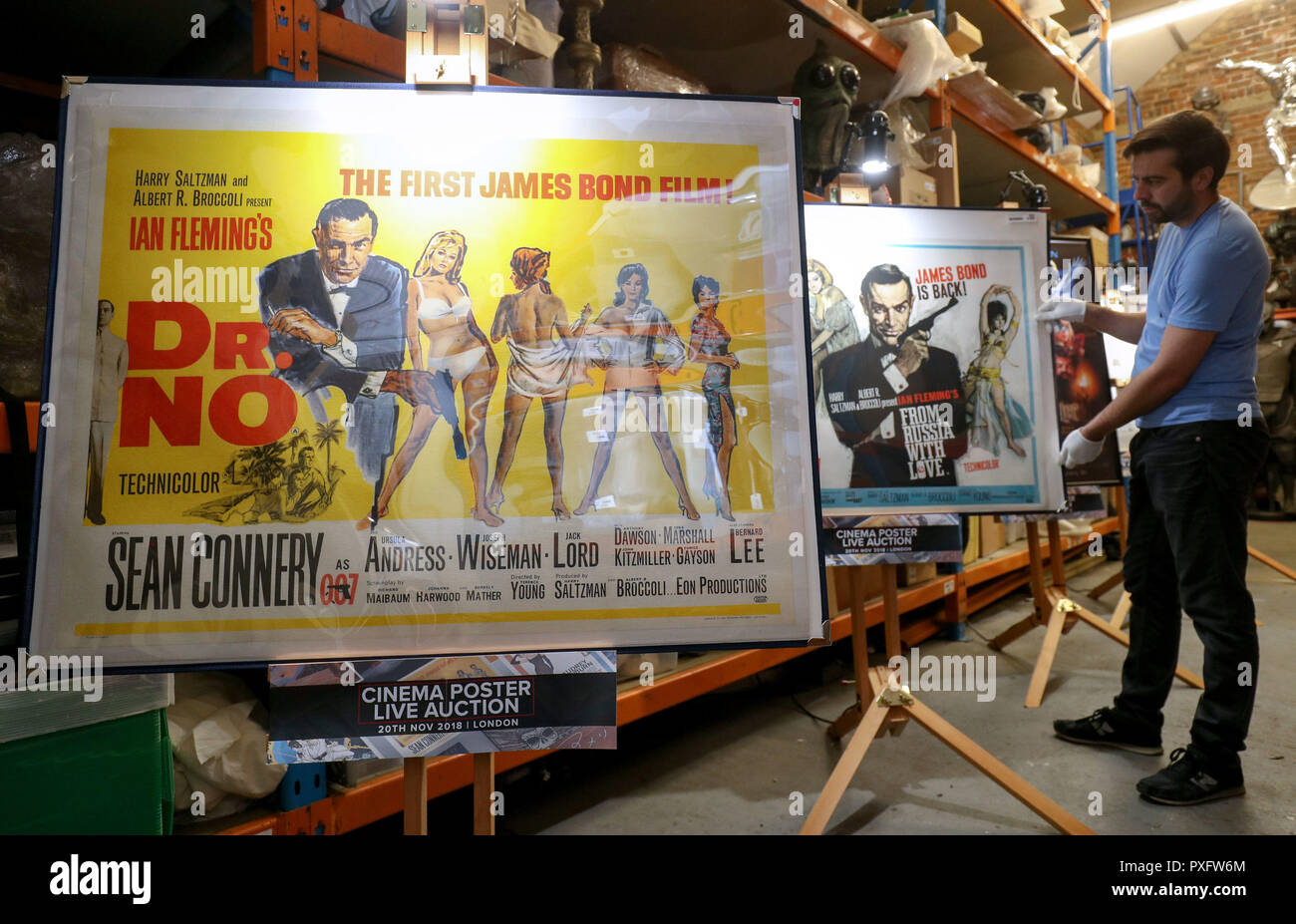 Prop Store Mitarbeiter Matt Geschichte passt ein Plakat für den James Bond Film 1963 aus Russland mit Liebe auf Anzeige neben einem Plakat für die 1962 Bond Film Dr No während eine Vorschau auf die bevorstehende Kino Plakat Auktion an der Prop Shop Head Office in der Nähe von Rickmansworth. Stockfoto